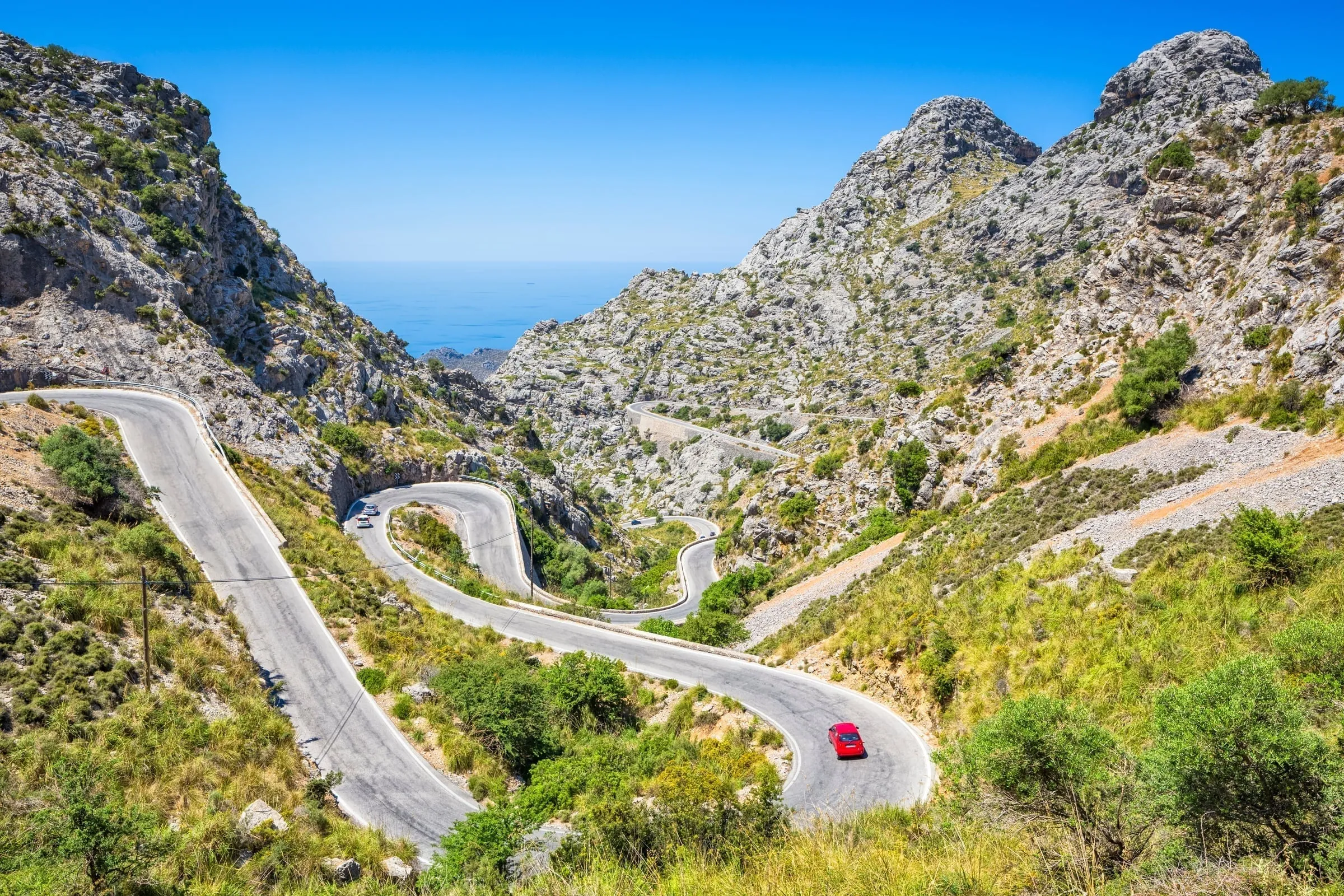 The famous Sa Calobra serpentine road in winter, wet limestone glistening after February rain, Tour de France cyclists training on the hairpin turns
