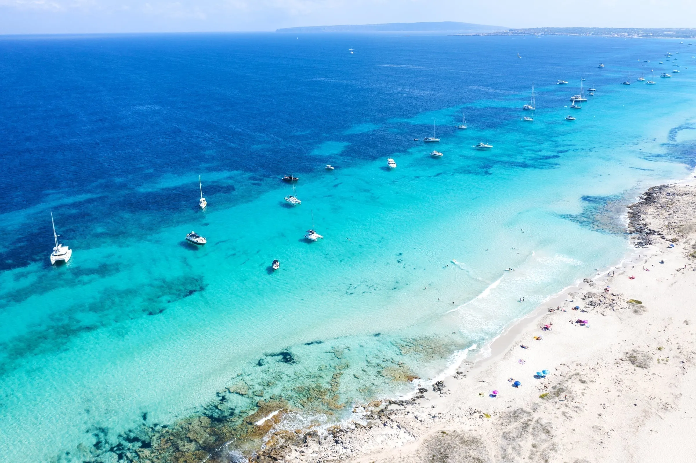 People sunbathing on Illetes beach with clear blue water