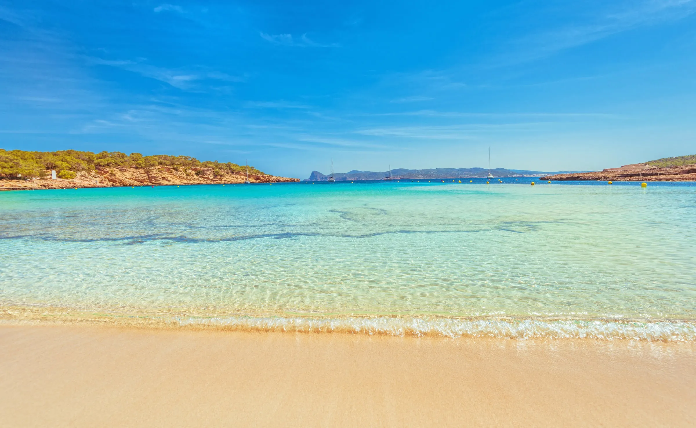 View of a pristine northern Ibiza cove with ochre cliffs and crystal-clear Mediterranean waters