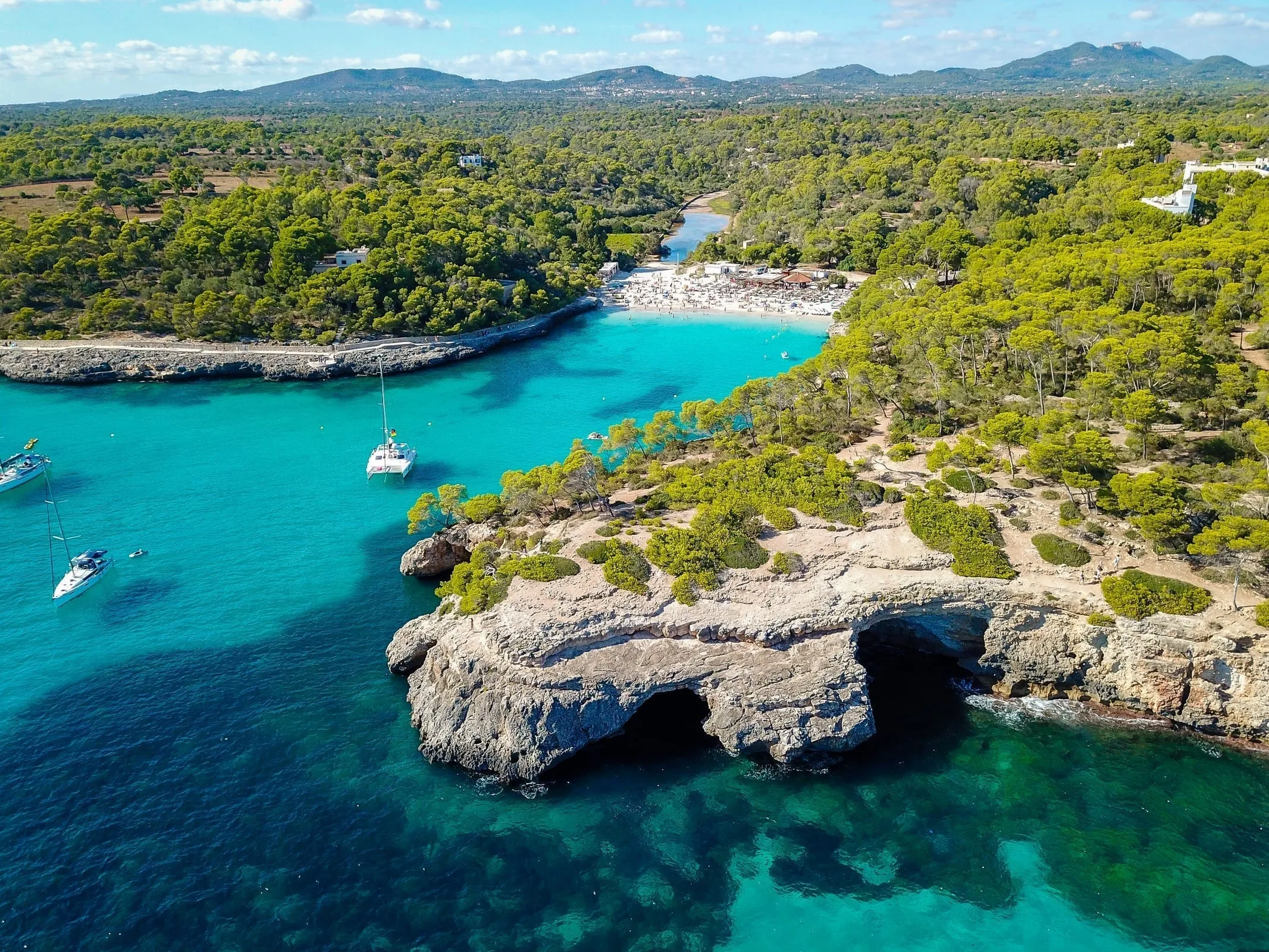Aerial view of Cala Llombards with boats anchored in turquoise waters